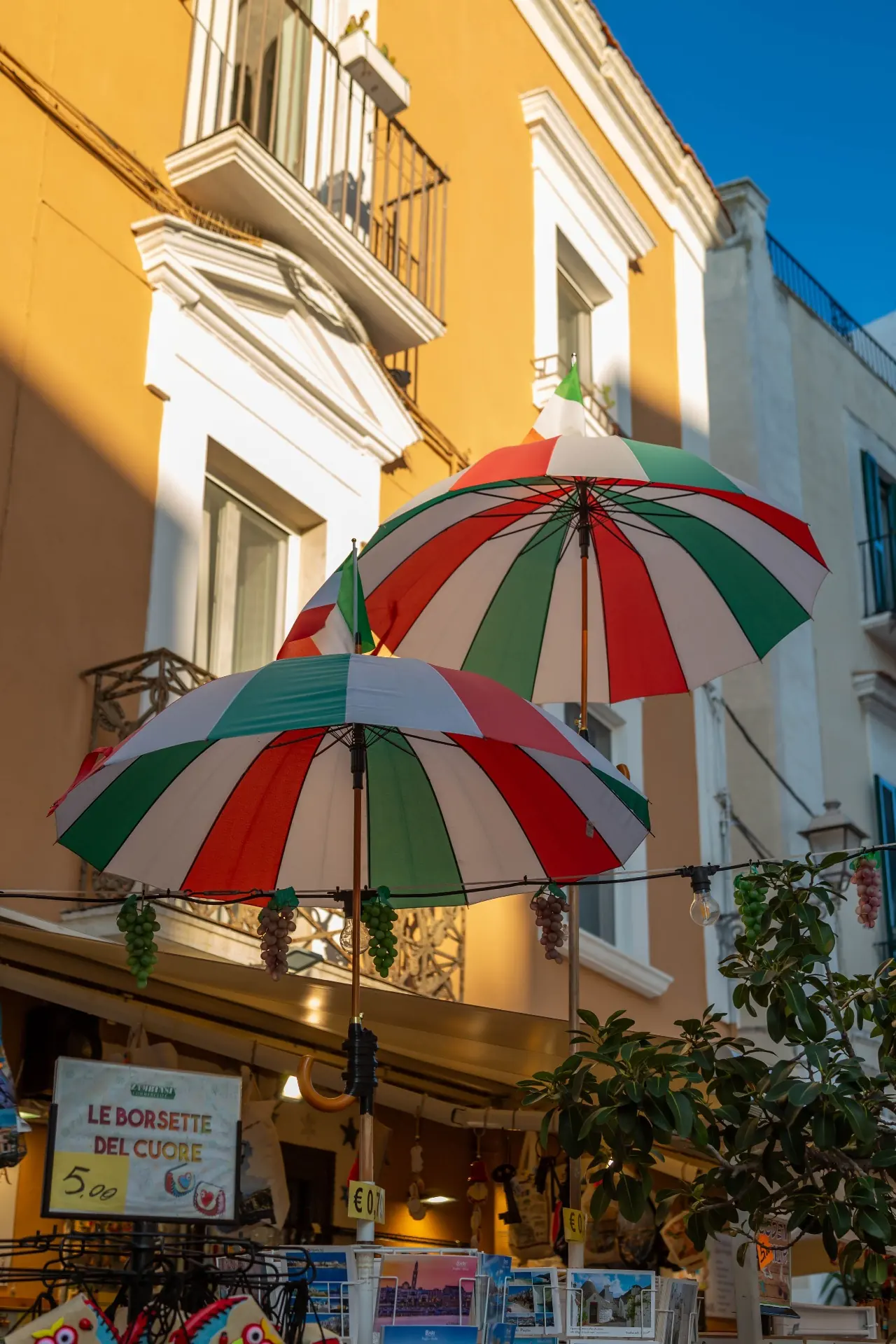 Sombrillas con los colores de Italia sobre una fachada en tono ámbar