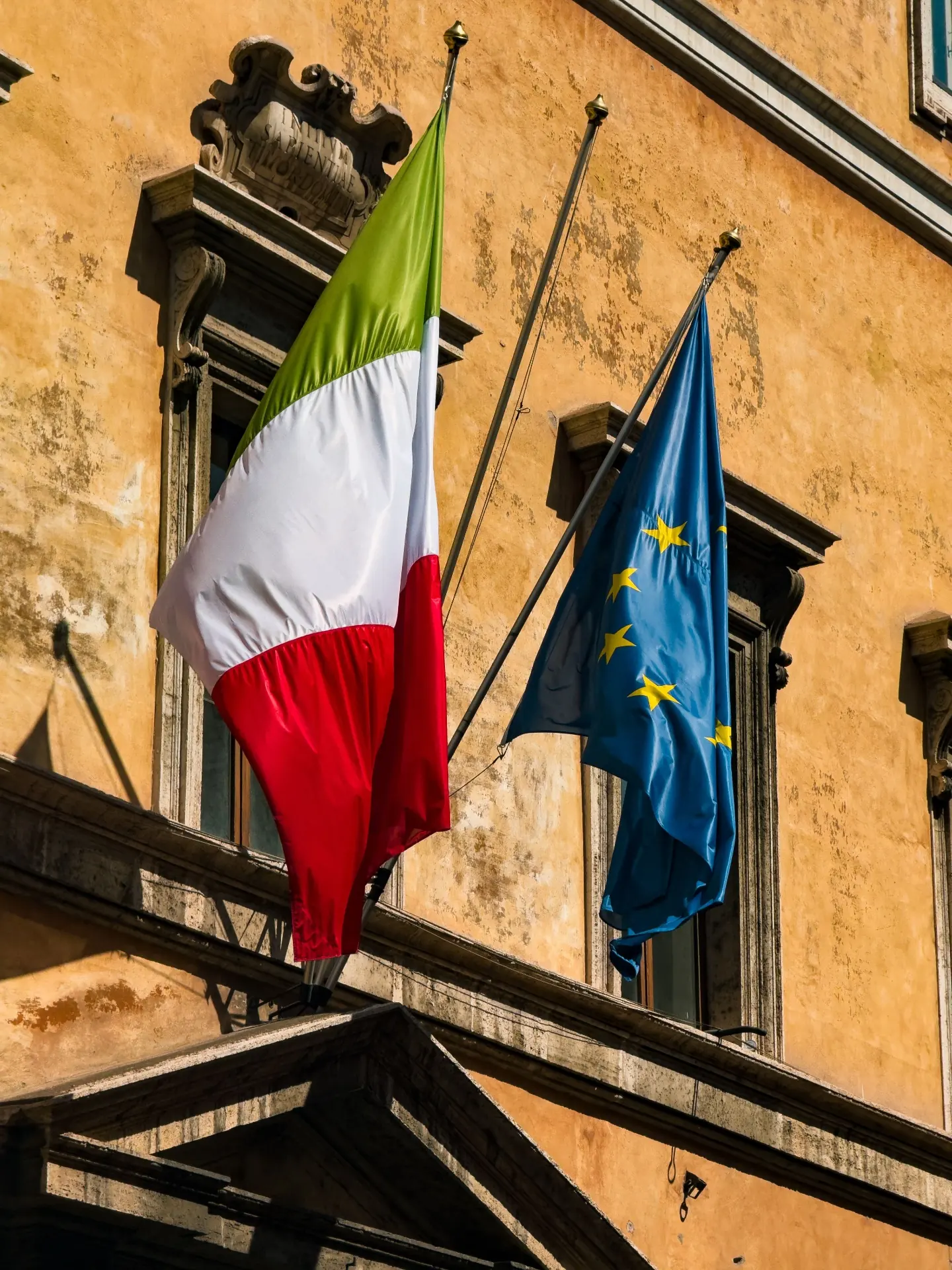 Bandera de Italia y de la Unión Europea en una fachada institucional en Roma