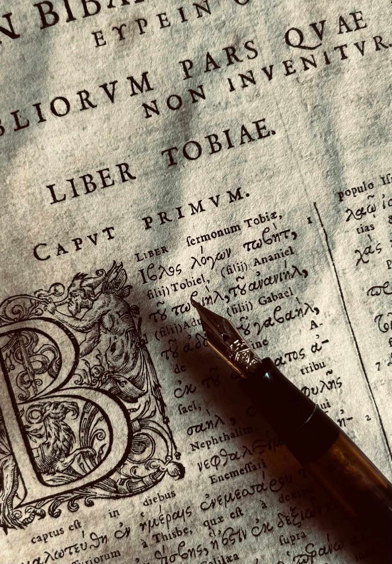 Libro antiguo con texto latino y griego manuscrito, y pluma estilográfica